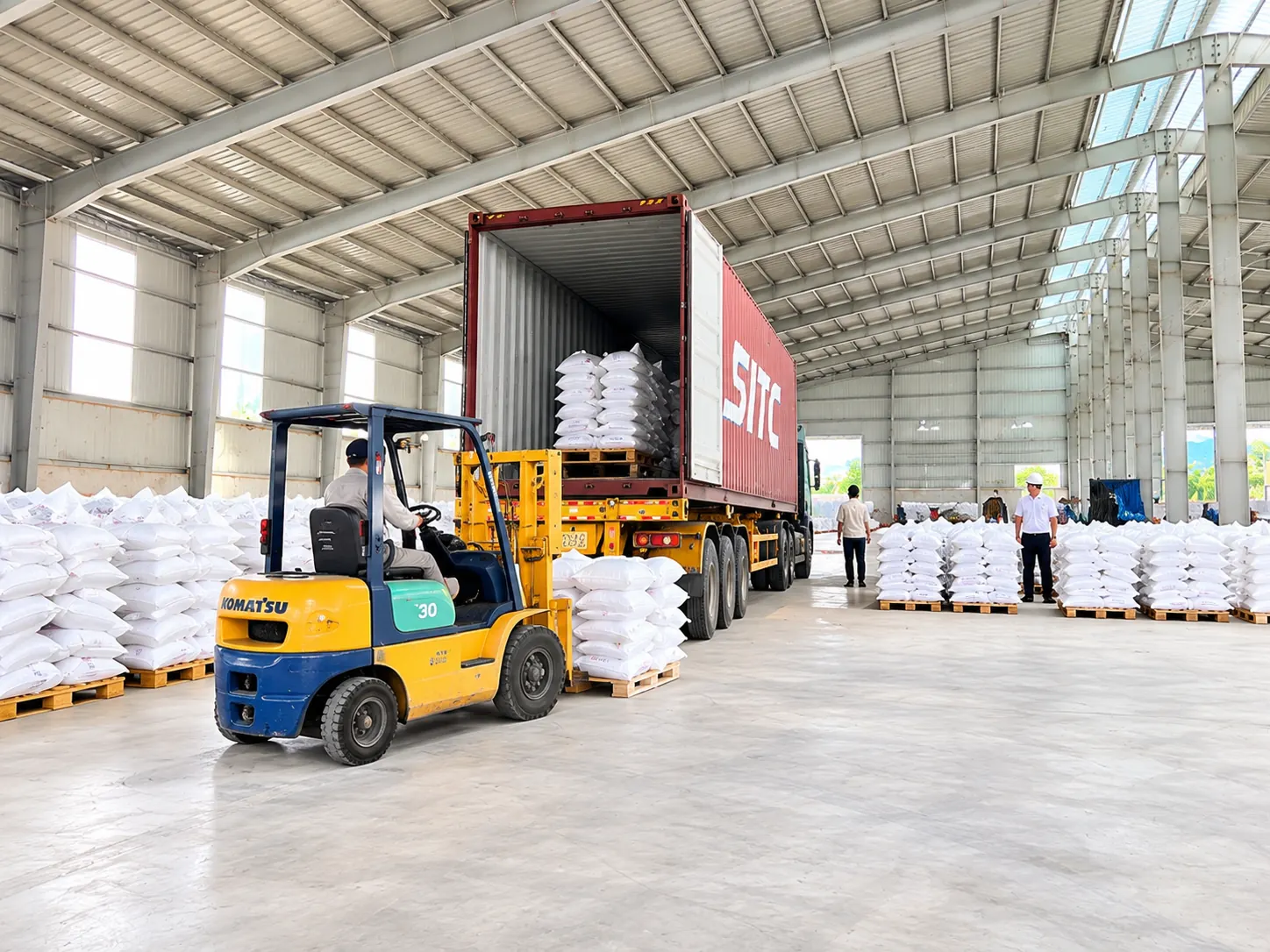 Forklift loading bagged cassava products into a container inside the warehouse