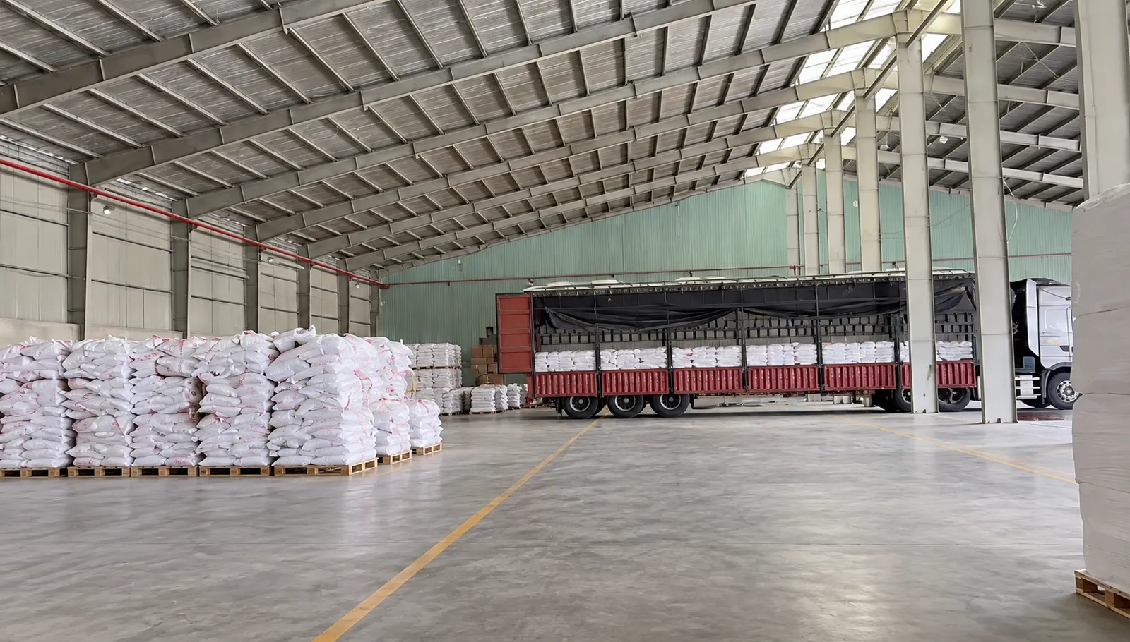 幸运星仓库内托盘码放的袋装木薯产品与正在装货的货车
